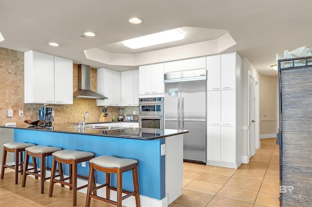 28107 Perdido Beach Blvd Unit D1005, Orange Beach, AL 36561 - kitchen with wall chimney exhaust hood, stainless steel appliances, a raised ceiling, a peninsula, and recessed lighting