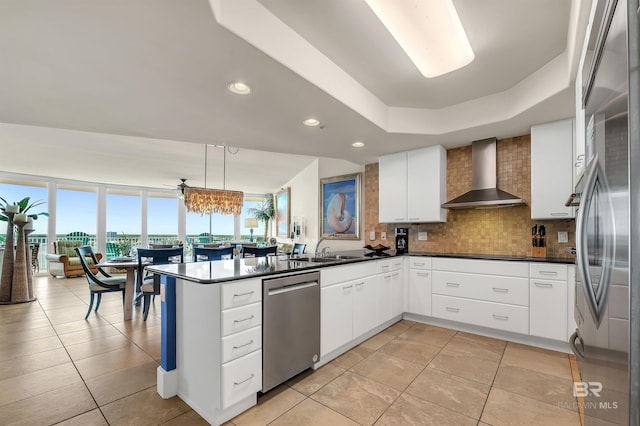 28107 Perdido Beach Blvd Unit D1005, Orange Beach, AL 36561 - kitchen featuring wall chimney range hood, stainless steel appliances, dark countertops, a peninsula, and backsplash
