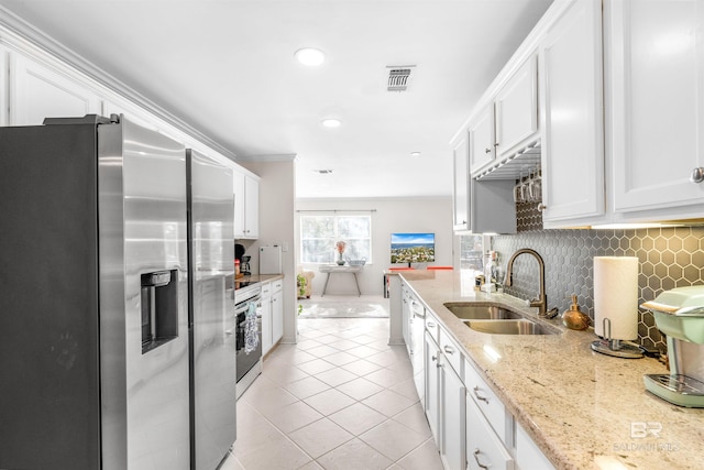 kitchen with light stone counters, stainless steel appliances, sink, light tile patterned floors, and white cabinets