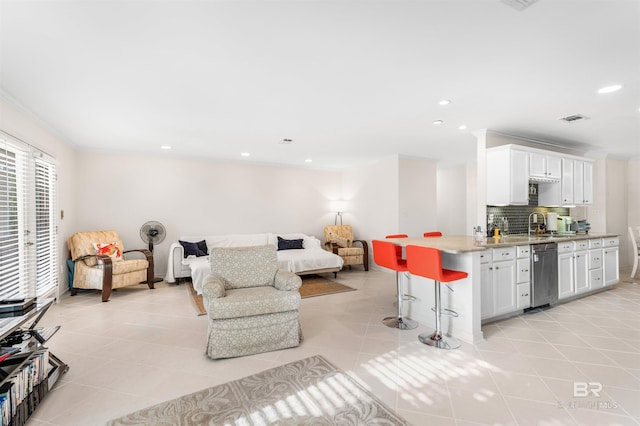 tiled living room featuring crown molding and sink