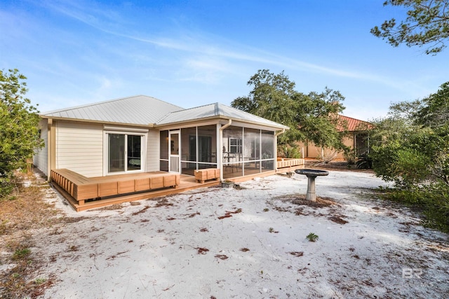 rear view of house featuring a sunroom and a deck