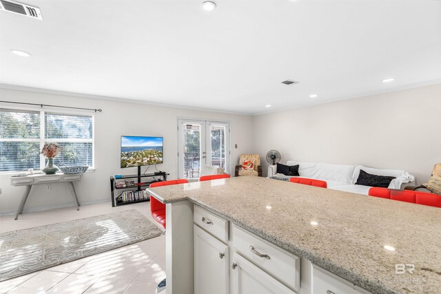 kitchen featuring white cabinets, french doors, light tile patterned floors, and light stone counters