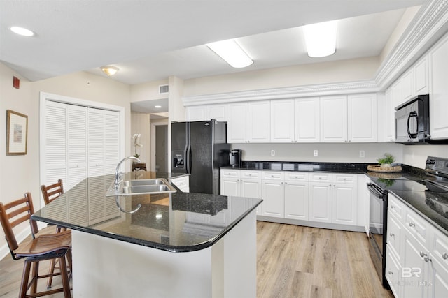 kitchen with black appliances, light wood finished floors, a sink, and white cabinetry
