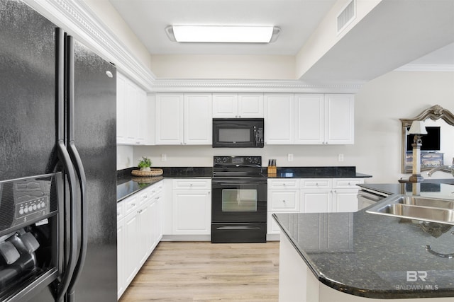 kitchen with a sink, visible vents, white cabinets, light wood-style floors, and black appliances