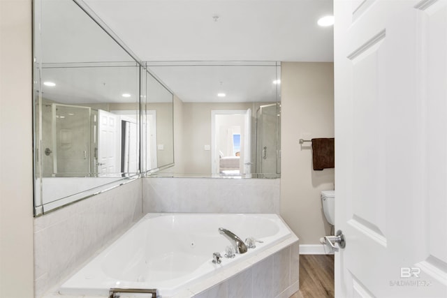 bathroom featuring a jetted tub, a stall shower, toilet, and wood finished floors