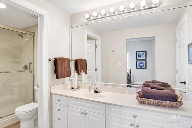 full bath with visible vents, vanity, a shower stall, and toilet
