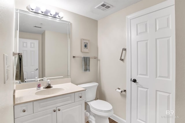bathroom featuring visible vents, vanity, and toilet