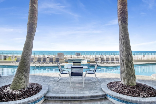 community pool featuring a patio area, fence, and a water view