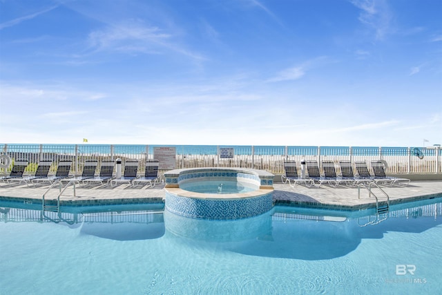 pool featuring a patio area, fence, a hot tub, and a water view