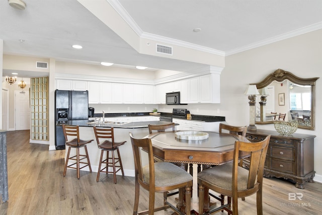 dining space featuring light wood-style floors, visible vents, a chandelier, and crown molding