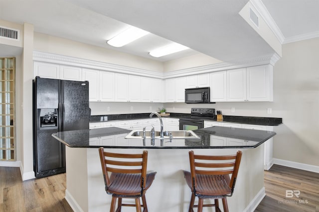 kitchen with a sink, visible vents, white cabinets, ornamental molding, and black appliances