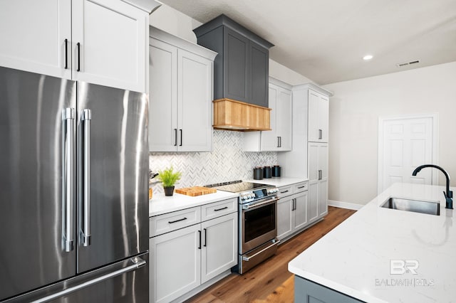 kitchen featuring appliances with stainless steel finishes, tasteful backsplash, light stone counters, sink, and dark hardwood / wood-style floors