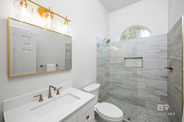 bathroom with a tile shower, vanity, and toilet