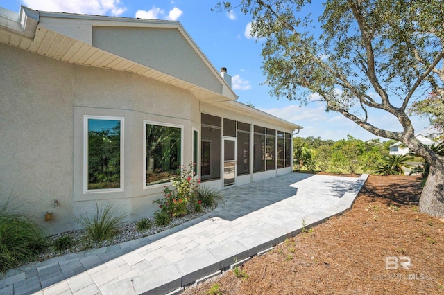 rear view of house featuring a sunroom and a patio area