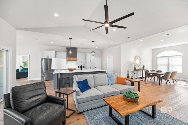 living room with light wood-type flooring, ceiling fan, and lofted ceiling