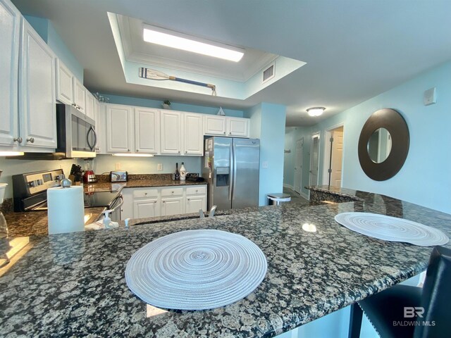 1010 W Beach Blvd Unit 209, Gulf Shores, AL 36542 - kitchen with stainless steel appliances, white cabinets, dark stone countertops, and a peninsula