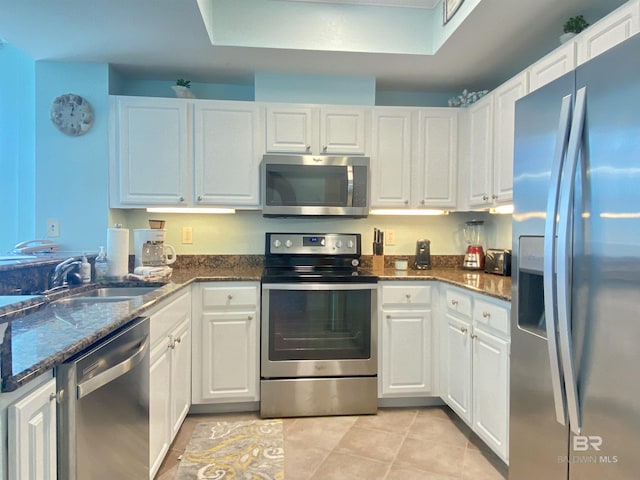 1010 W Beach Blvd Unit 209, Gulf Shores, AL 36542 - kitchen featuring stainless steel appliances, white cabinets, light tile patterned floors, and dark stone countertops