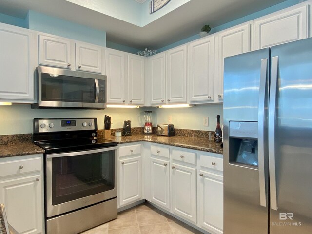 1010 W Beach Blvd Unit 209, Gulf Shores, AL 36542 - kitchen with stainless steel appliances, white cabinets, light tile patterned flooring, and dark stone counters