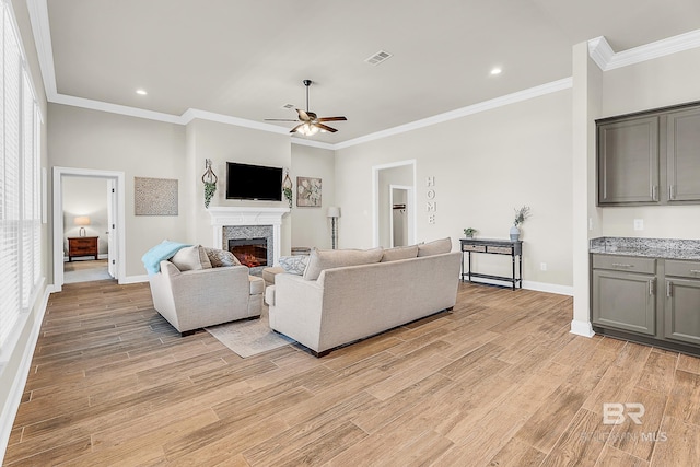 living area featuring light wood-style floors, visible vents, a lit fireplace, and baseboards