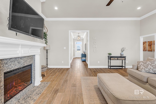 living area with ornamental molding, baseboards, a tiled fireplace, and wood finished floors