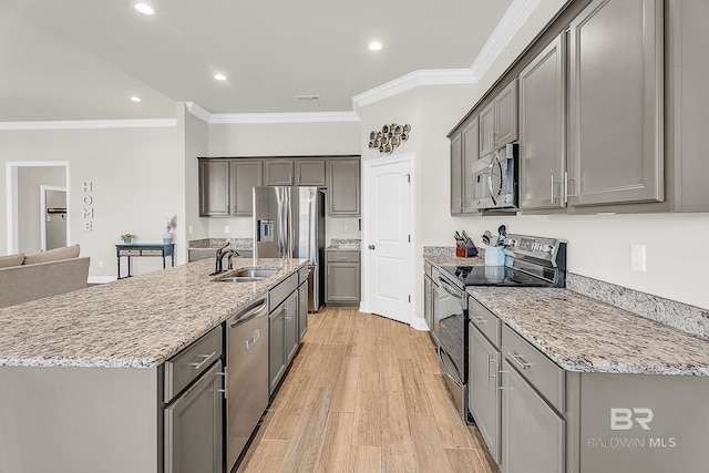 kitchen with a sink, light wood-style floors, appliances with stainless steel finishes, light stone countertops, and crown molding