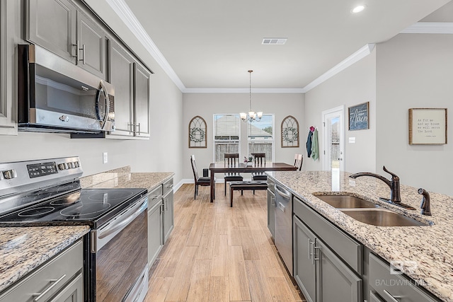 kitchen featuring appliances with stainless steel finishes, crown molding, a sink, and light wood-style flooring
