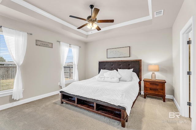 bedroom with a tray ceiling, carpet, visible vents, and baseboards