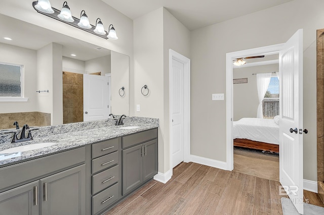full bath with a sink, baseboards, and wood finished floors