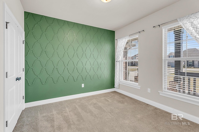 empty room with an accent wall, carpet flooring, baseboards, and wallpapered walls