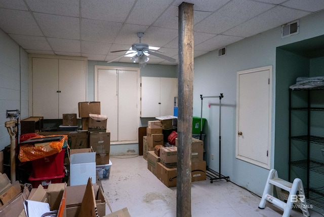 basement with a paneled ceiling and ceiling fan