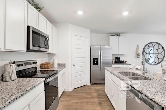 kitchen featuring stainless steel appliances, light stone countertops, white cabinets, and light hardwood / wood-style flooring