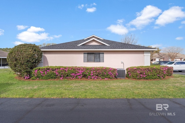 view of side of home with stucco siding and a yard