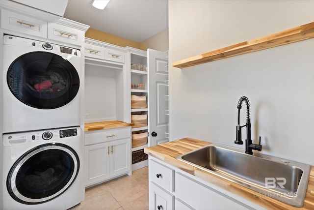 laundry area featuring cabinets, light tile patterned floors, stacked washer and dryer, and sink