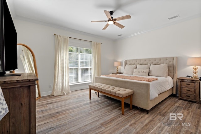 bedroom featuring light hardwood / wood-style floors, ceiling fan, and crown molding