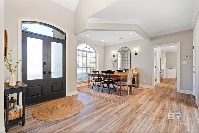 entrance foyer with crown molding, light hardwood / wood-style flooring, and french doors