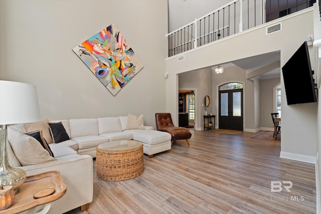 living room featuring french doors, wood-type flooring, and a high ceiling