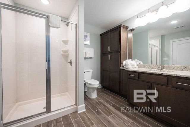 bathroom featuring visible vents, vanity, toilet, wood finish floors, and a shower stall