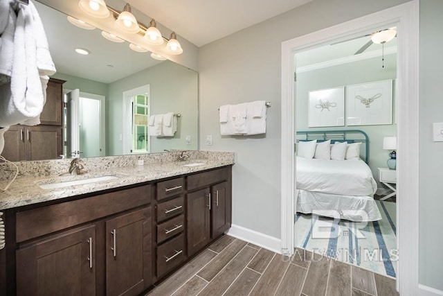 full bath with a sink, baseboards, double vanity, and wood finished floors
