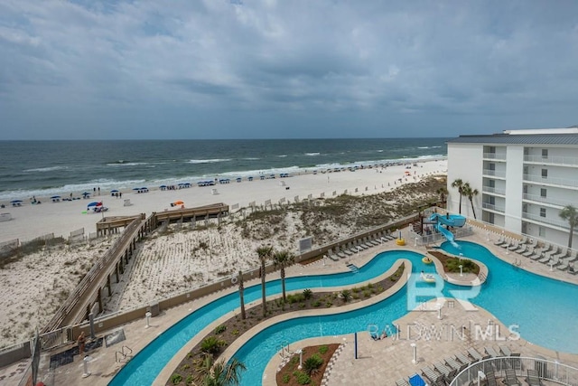pool featuring a water view, a water slide, and a beach view