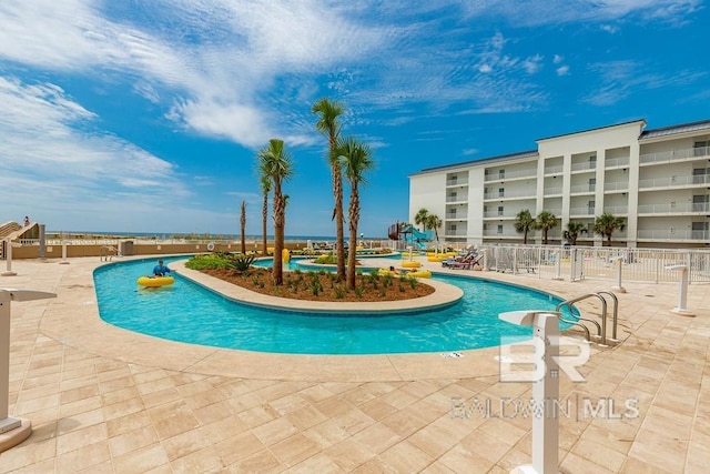 community pool with fence and a patio area