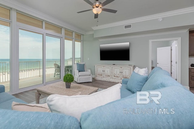living area featuring crown molding, a ceiling fan, wood finished floors, and visible vents