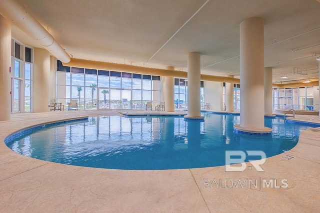 community pool featuring glass enclosure and a patio area
