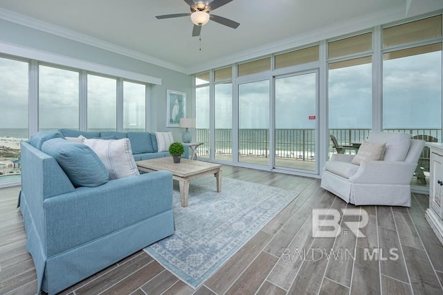 living room featuring ornamental molding, wood finished floors, a wall of windows, ceiling fan, and a water view