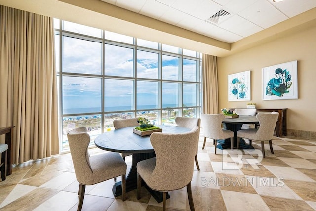 dining room featuring expansive windows, a water view, visible vents, and a healthy amount of sunlight