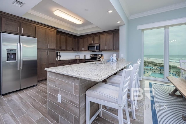 kitchen with visible vents, crown molding, appliances with stainless steel finishes, dark brown cabinets, and a peninsula