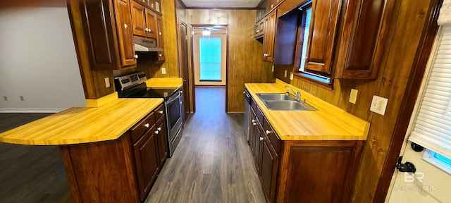 kitchen featuring a textured ceiling, appliances with stainless steel finishes, dark hardwood / wood-style flooring, wooden walls, and sink