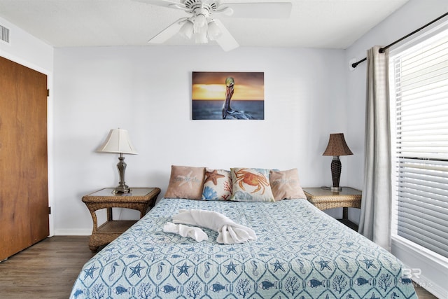 bedroom with baseboards, visible vents, a ceiling fan, and wood finished floors