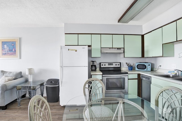 kitchen featuring light wood finished floors, light countertops, a sink, white appliances, and under cabinet range hood