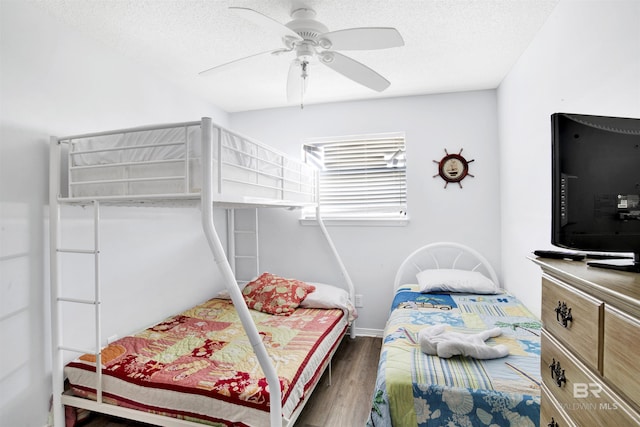 bedroom with ceiling fan, a textured ceiling, baseboards, and wood finished floors