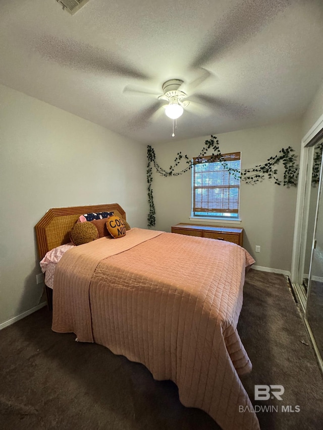 bedroom with dark colored carpet, ceiling fan, and a textured ceiling